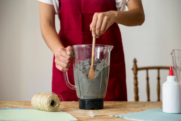 Midsection view of a woman's hand stirring paper pulp in blender