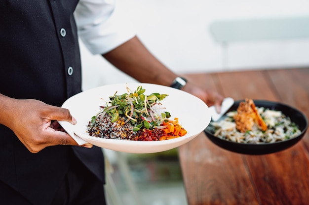 Midsection of a waiter serving two dishes on a wooden table