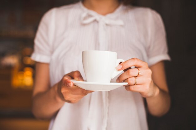 Midsection of woman holding coffee cup while standing in restaurant