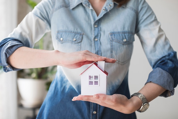 Midsection of woman protecting house model at office