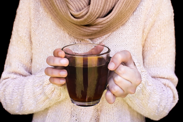 Free photo midsection of a woman wearing woolen sweater holding glass cup of herbal tea