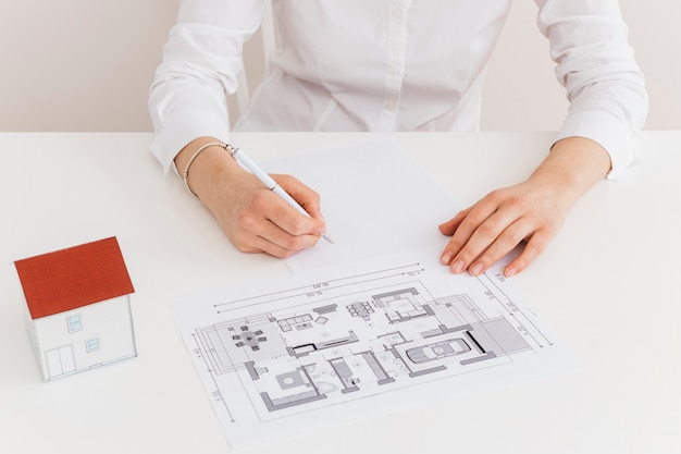 Midsection of woman working on house blueprint at desk in office