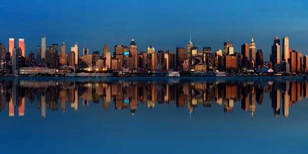 Midtown Manhattan skyline with reflections at dusk panorama over Hudson River