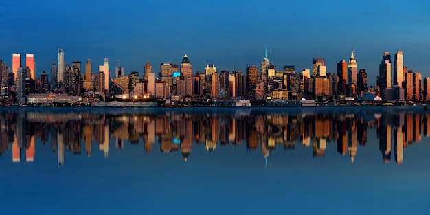 Midtown Manhattan skyline with reflections at dusk panorama over Hudson River