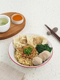 チキンミートボール​餃子​と​野菜​が​入った​三重​アヤム​麺​は​インドネシア​で​人気​の​食べ物​です
