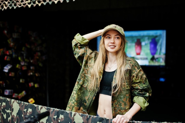 Military girl in camouflage uniform against army background on shooting range