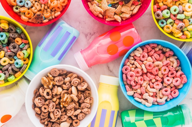 Milk bottles with bowls of cereal on marble table