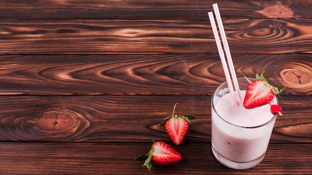 Milk cocktail with strawberry on wooden surface