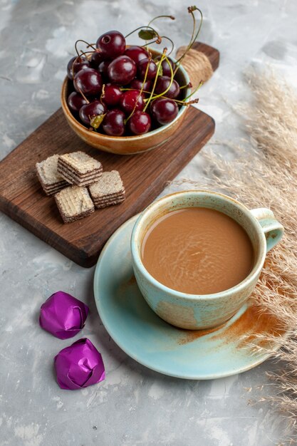 milk coffee with waffles and fresh sour cherries on light desk