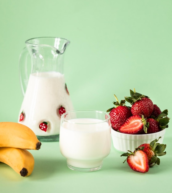 녹색 배경의 건강한 식습관과 영양 생활 방식에 신선한 딸기와 바나나 우유