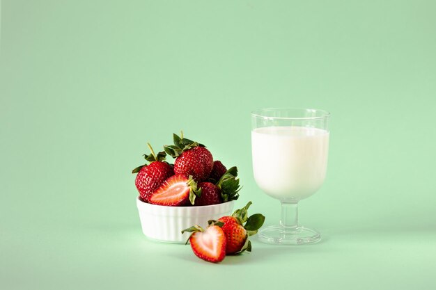 Milk and fresh strawberries on a green background healthy diet and nutrition lifestyle