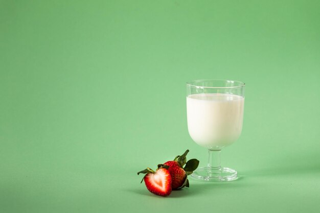 Milk and fresh strawberries on a green background healthy diet and nutrition lifestyle