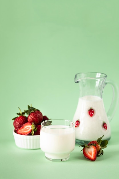緑の背景の健康的な食事と栄養のライフ スタイルに牛乳と新鮮なイチゴ