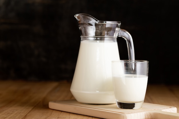 milk in glass and jug on wooden table