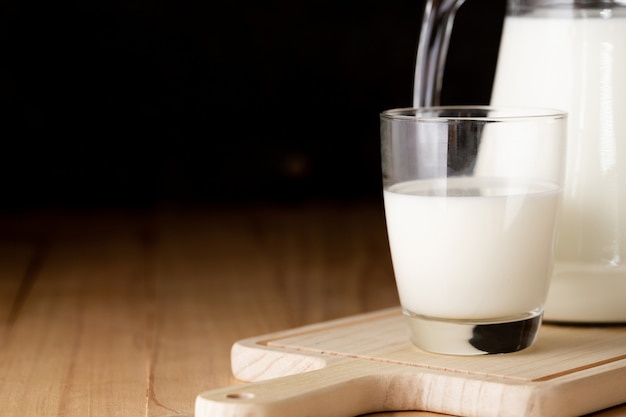 milk in glass and jug on wooden table
