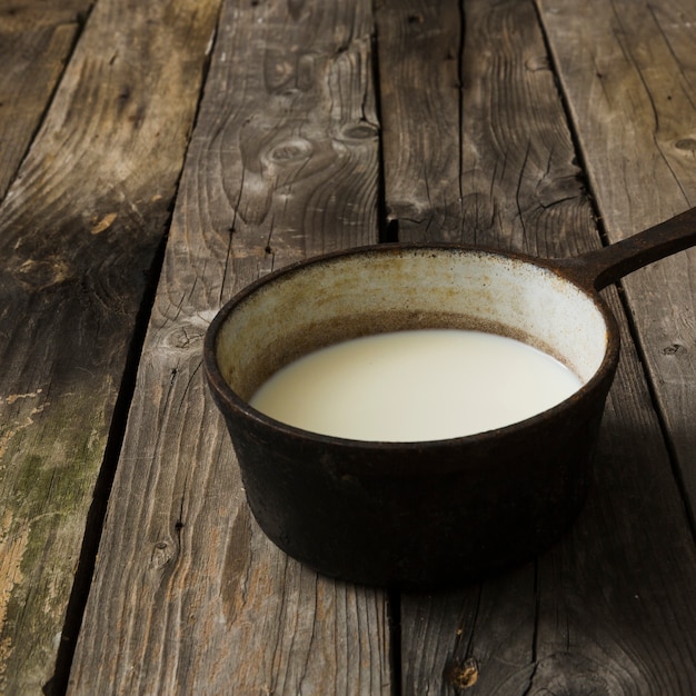 Latte nella vecchia casseruola vintage sul vecchio tavolo di legno