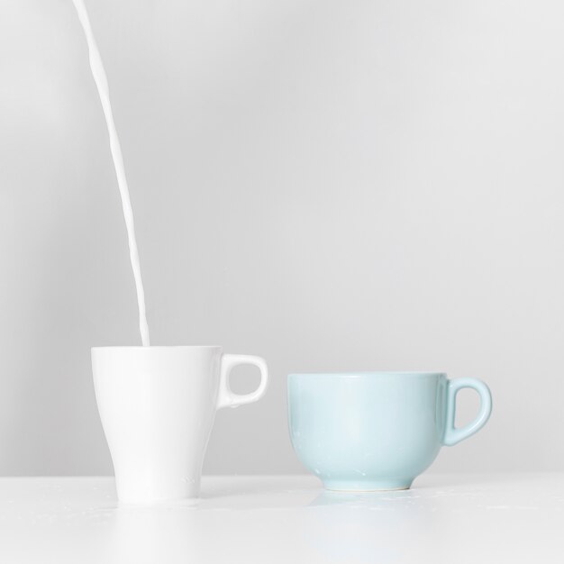 Milk pouring into ceramic mug on a table