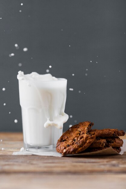 Milk splashed in glass with cookies