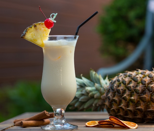 Free photo milky cocktail in glass with pinapple slice and a cherry.