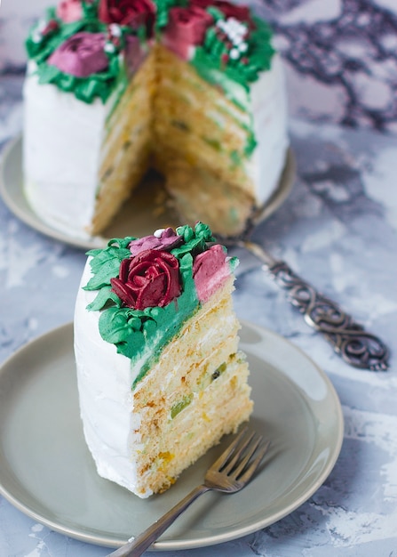 Кусочек торта молочной девочки украшен зелеными листьями и цветами лилии, торт украшен цветочным букетом, декор весенний торт