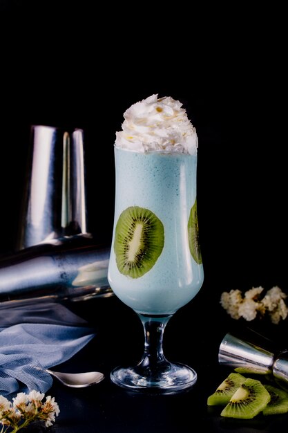 Milky smoothie in a glass with cream and kiwi.