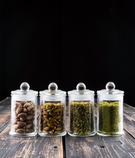 milled, crushed or granulated pistachios in glass jars on dark wooden