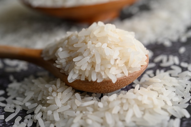 Free photo milled rice in a bowl and a wooden spoon on the black cement floor.