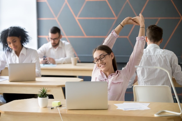 Millennial employee stretching taking break from computer work for relaxation