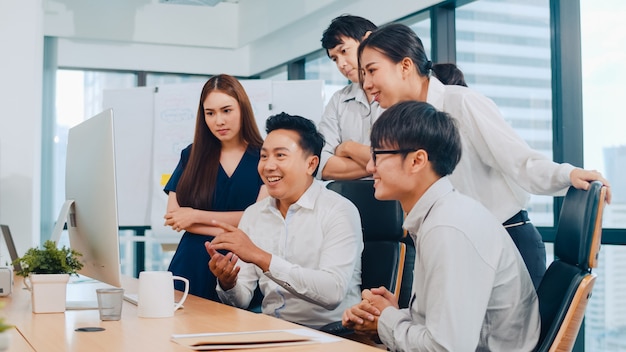 Millennial group of young businesspeople Asia businessman and businesswoman celebrate giving five after dealing feeling happy and signing contract or agreement at meeting room in small modern office.