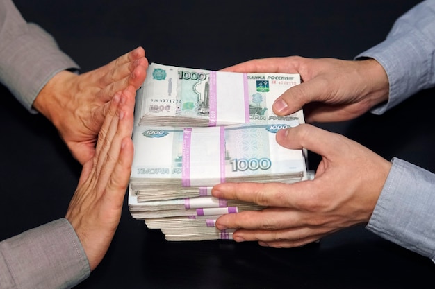 A million rubles in men's hands. bribery in russian rubles in a dark room. the concept of corruption and bribery. the rejection of money. honest official refuses a bribe. Premium Photo