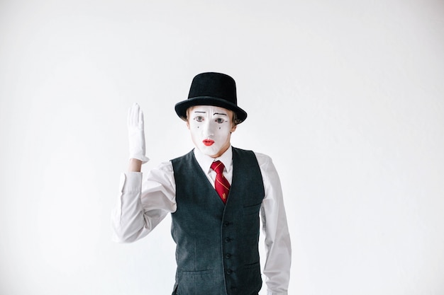 Mime in black hat holds his hand up like a pupil