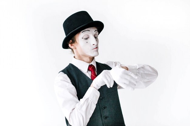 Mime in black hat and waistcoat looks at the invisible watch