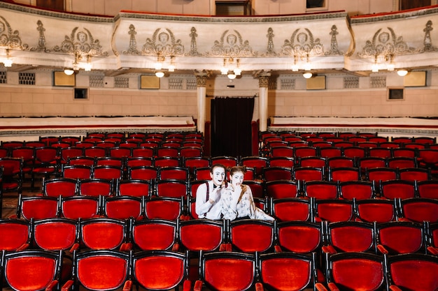 Mime couple artist sitting together on chair in auditorium