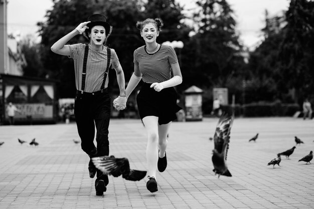 Mime couple holding hands running on pavement