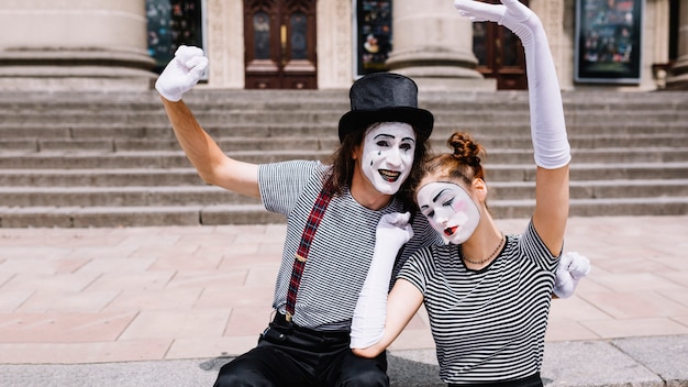 Free photo mime couple raising their arms