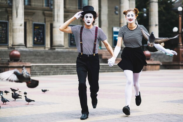 Mime couple running on city pavement