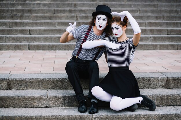 Mime couple sitting on staircase making gestures