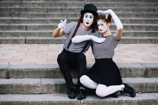 Mime couple sitting on staircase making gestures