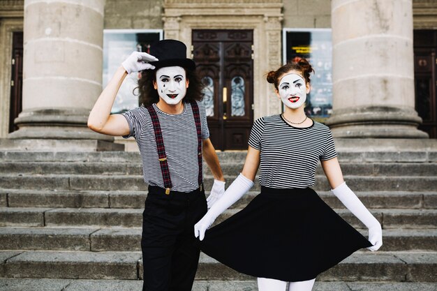 Mime couple standing in front of staircase greeting