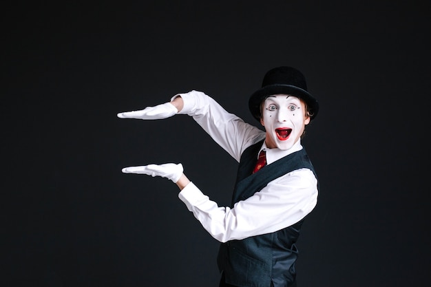 Free photo mime holds his palms parallel in the air