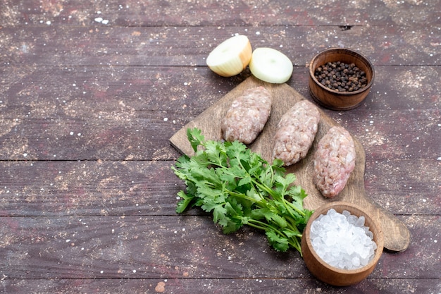 minced raw meat cutlet formed with greens onions salt on brown desk