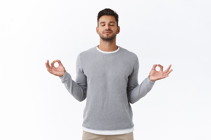 Free Photo mindful patient and relaxed young happy man, practice breathing exercises, hold hands sideways and smiling relieved, release stress during work time take break to meditate, white wall