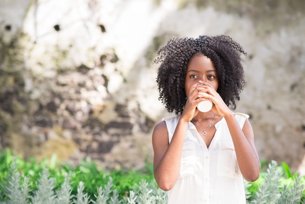 Mindful young woman drinking coffee outdoors