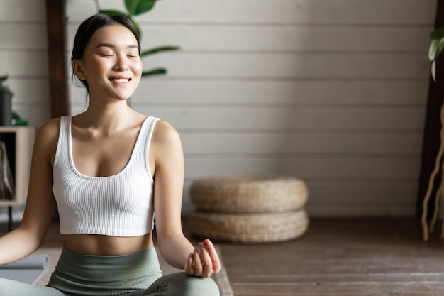 Free photo mindfulness and meditation concept young asian woman doing workout at home yoga meditation in living...