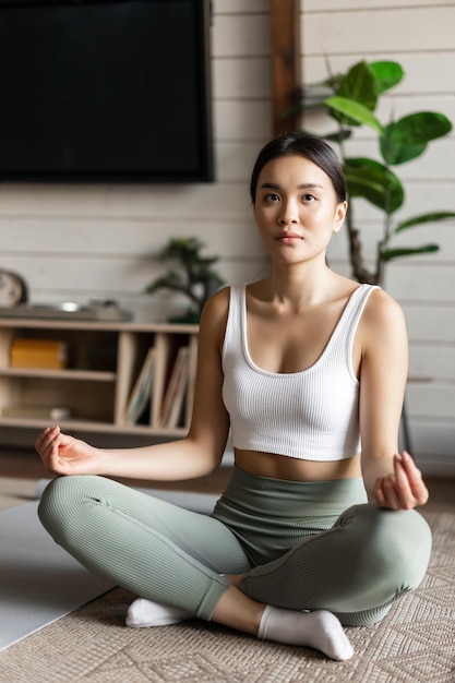 Mindfulness and meditation concept young asian woman doing workout at home yoga meditation in living...