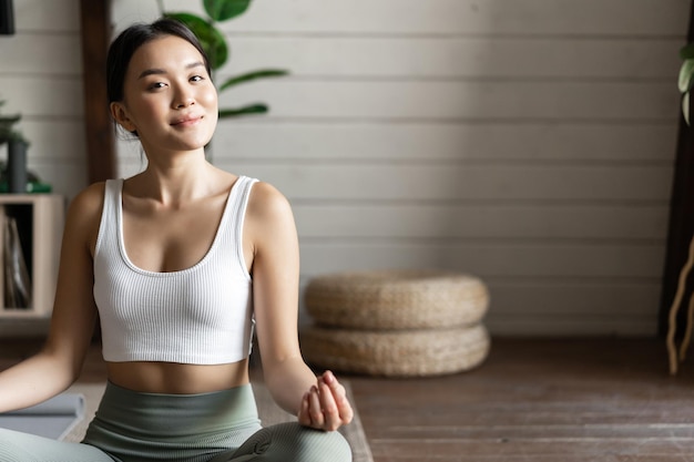 マインドフルネスと瞑想の概念生活の中で自宅でヨガ瞑想でトレーニングをしている若いアジアの女性...