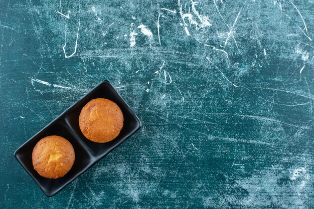 Mini cakes in a dish , on the blue table. 