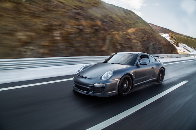 Free photo mini coupe driving on the highway accross mountains.