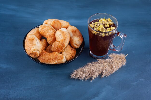 Mini croissants made of puff pastry with a golden crust and a cup of tea. 