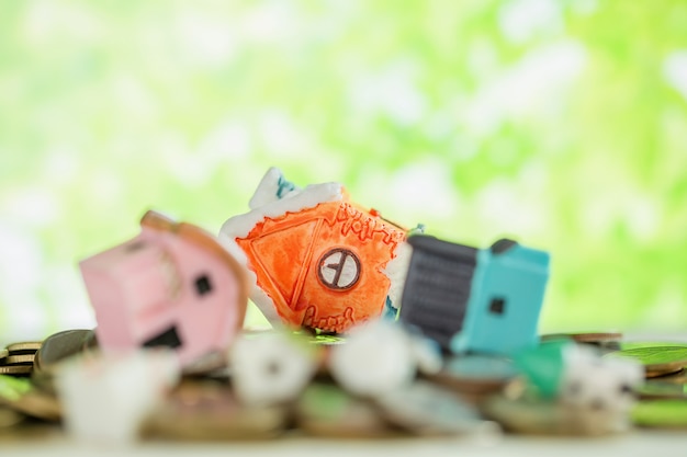 Mini house on pile of coins with green blur. 